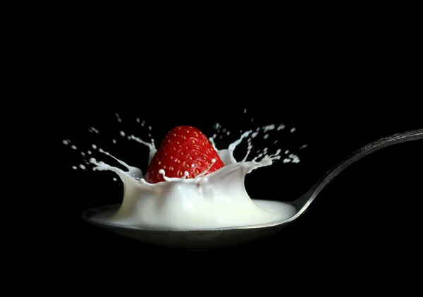 Strawberry splashing into milk in the spoon — Stock Photo, Image