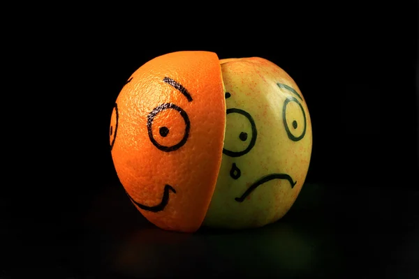 Trauriger Apfel mit fröhlicher orangefarbener Maske — Stockfoto