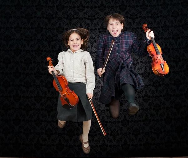 Two girls with violins jumping — Stock Photo, Image