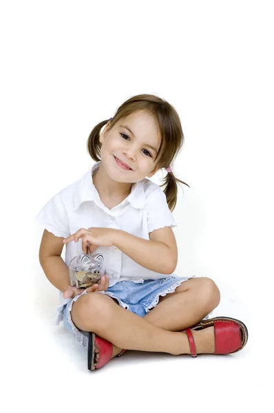 Malá holčička dát peníze do prasátko — Stock fotografie