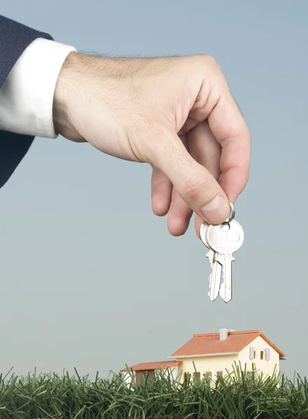 Hand med nycklar och ett litet hus — Stockfoto