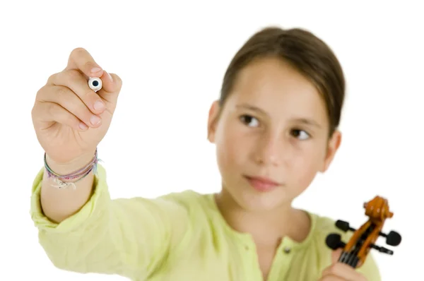 Молодая девушка пишет ручкой и держит скрипку — стоковое фото