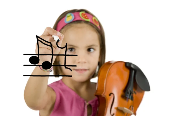 Little girl writing with a pen and holding a violin — Stock Photo, Image