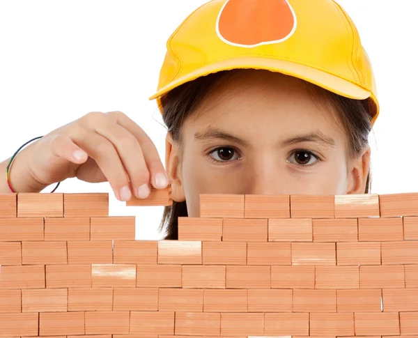 Klein meisje bouwen van een muur geïsoleerd op witte achtergrond — Stockfoto