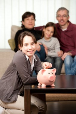 Young girl saving money on a piggy bank clipart