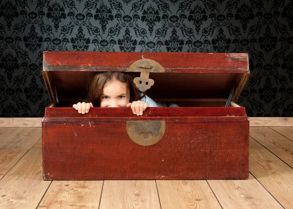 Klein meisje in een oude kofferbak — Stockfoto