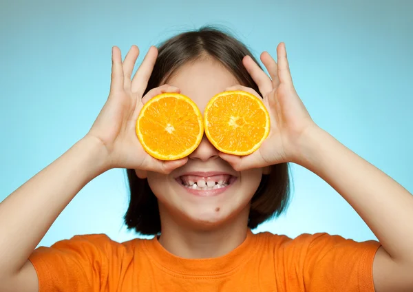 Little girl using oranges as glasses — Stock Photo, Image