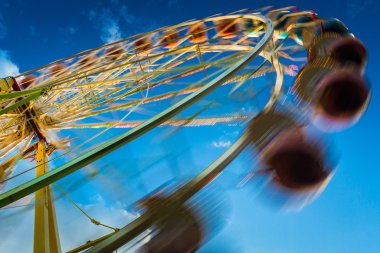 Blurry ferris wheel in motion on blue sky background clipart