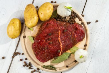 Raw steak spiced with herbs ready for baking clipart