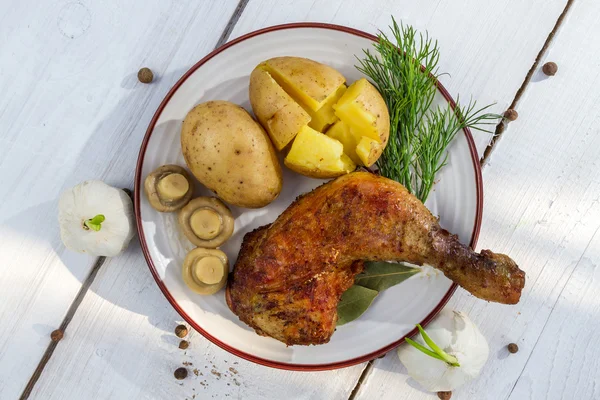 Leg of chicken served with potatoes in jackets — Stock Photo, Image