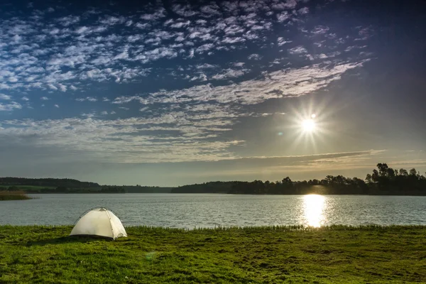 stock image White tent, sun and clounds on the lake in summer