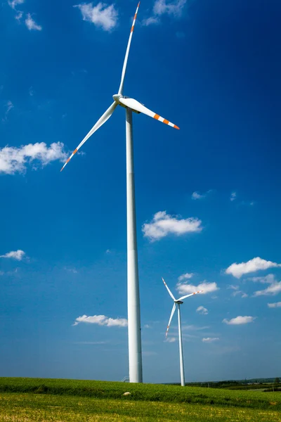 Turbine eoliche su campo verde con sfondo cielo blu — Foto Stock