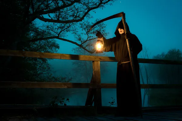 Człowiek na stary most z kosą i ropy naftowej lampy — Zdjęcie stockowe