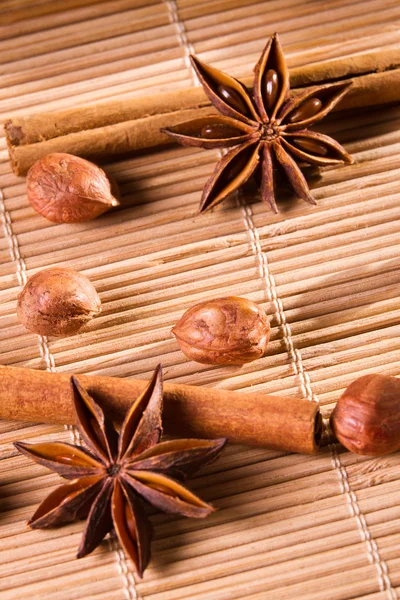 Closeup nuts and star anise on wooden bamboo mat — Stock Photo, Image
