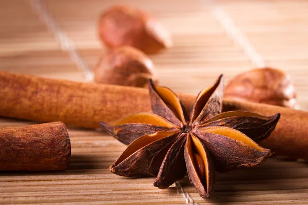 Closeup star anise and cinnamon bark on wooden bamboo mat — Stock Photo, Image