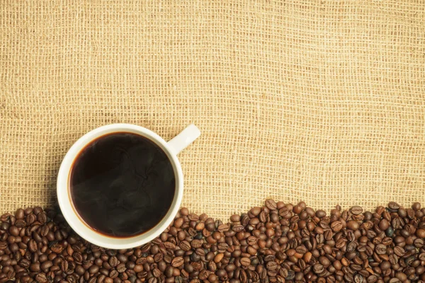 Granos de arpillera y café con fondo de taza — Foto de Stock