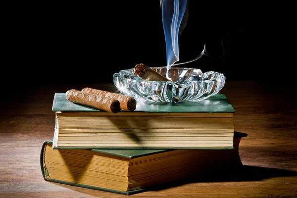 Blue smoke from cigar with ashtray and two books volume