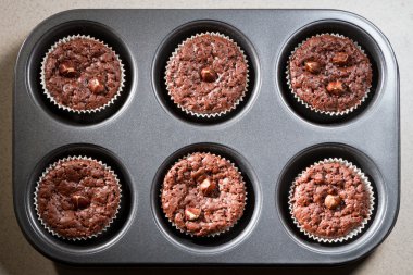 Six chocolate muffins in baking tray clipart