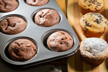 Vanilla and chocolate muffins in baking tray clipart