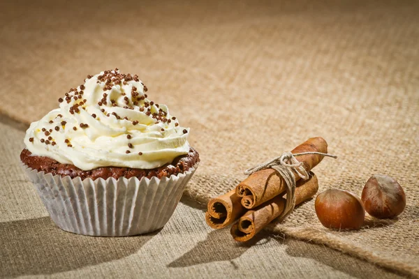 Chocolate muffin with vanilla cream and cinnamon and hazelnuts — Stock Photo, Image