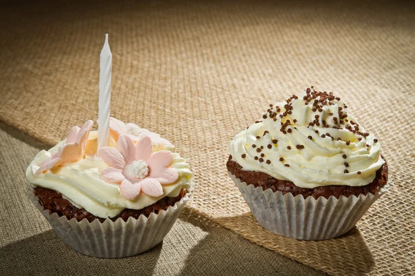Due muffin al cioccolato con candela e crema alla vaniglia — Foto Stock