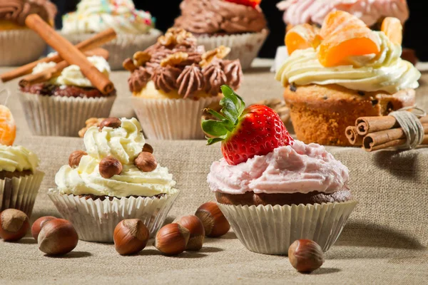 Various muffins with cream, fruits and nuts — Stock Photo, Image