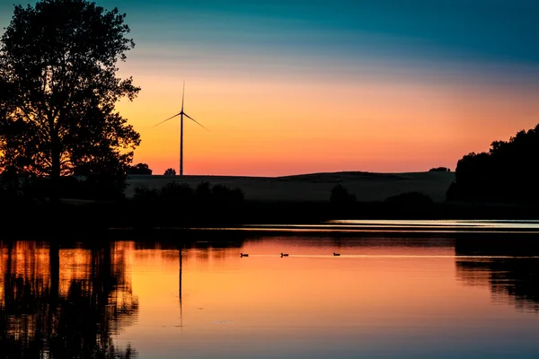 Éolienne et coucher de soleil au lac en été — Photo