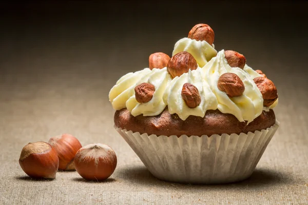 stock image Closeup muffin with vanilla cream and hazelnuts