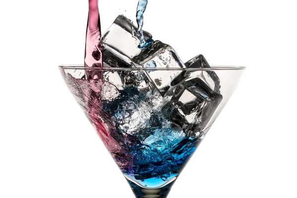 Niebieski i czerwony likier przelewa się do szklanki z kostkami lodu na biały — Zdjęcie stockowe