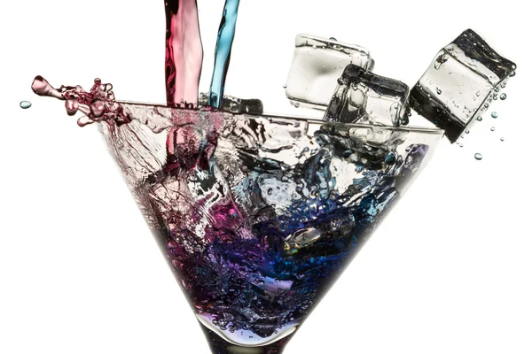 Versare il liquore rosso e blu in un bicchiere con cubetti di ghiaccio su b bianco — Foto Stock