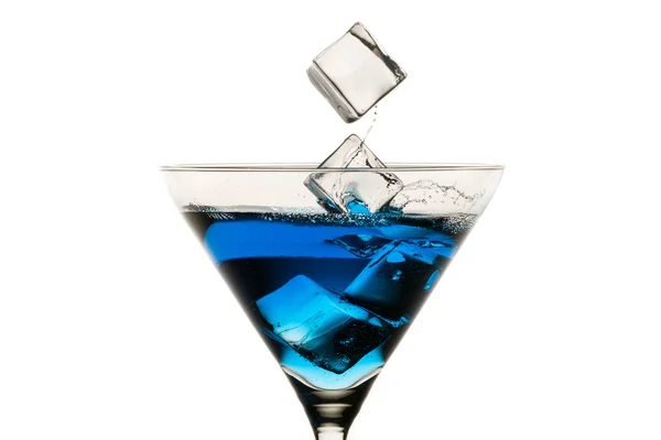 Deixando cair cubos de gelo em copos de martini no fundo branco — Fotografia de Stock