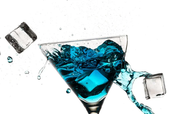 Ice cubes breaking martini glass filled with blue liqueur on whi — Stock Photo, Image
