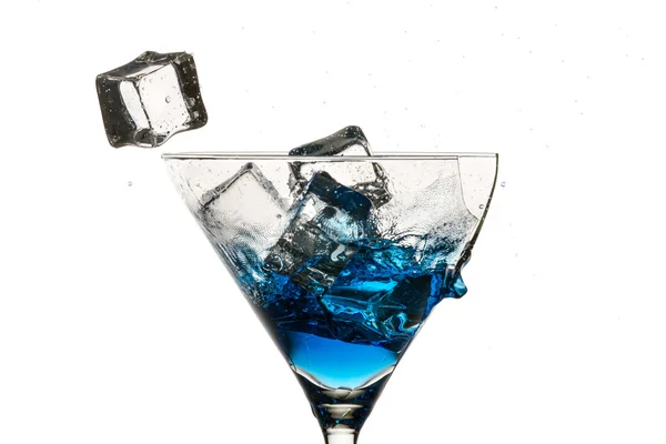 Cubes de glace et verre de martini cassé avec liqueur bleue sur ba blanc — Photo