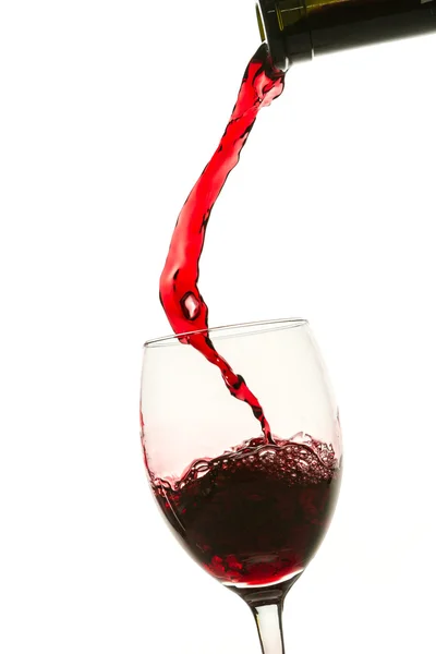 Наливание красного вина в бокал из бутылки на белом фоне — стоковое фото