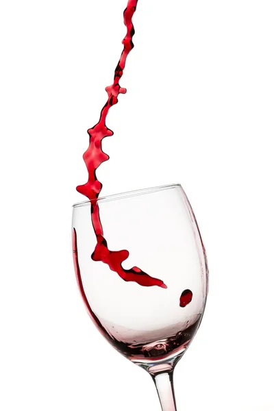 Bir kırmızı şarap cam içine beyaz zemin üzerine dökülen dere — Stok fotoğraf