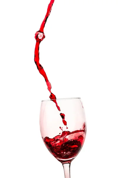 Il flusso di vino rosso versato in un bicchiere su sfondo bianco — Foto Stock