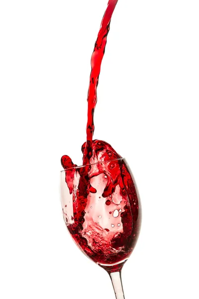 Проливание красного вина в стакан на белом фоне — стоковое фото