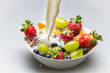 Milk pouring into dish with fresh fruits clipart