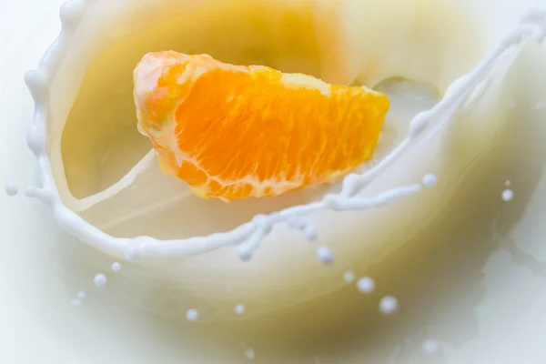 Closeup mandarin flowing into milk — Stock Photo, Image