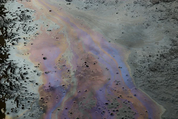 Нефть, плавающая в воде в грязи — стоковое фото