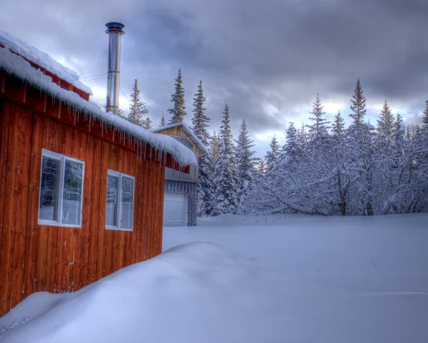 Huis in de winter met ijspegels en sneeuw — Stockfoto