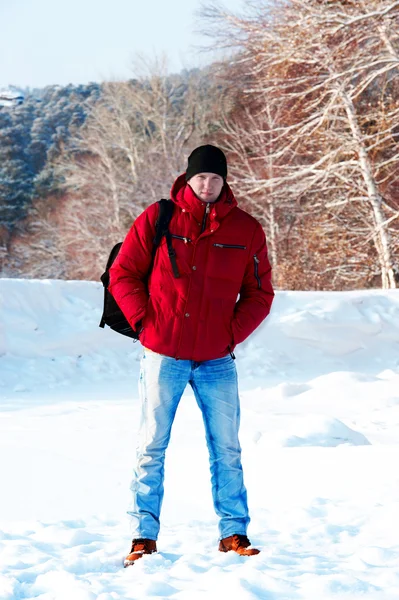 stock image Young guy in a red jacket on the background of the snow forest