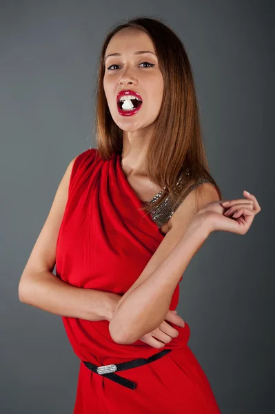 Modelo sexy em um vestido vermelho com açúcar na boca — Fotografia de Stock