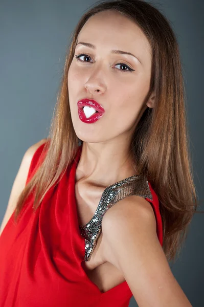Menina bonita com um açúcar em forma de coração na boca — Fotografia de Stock