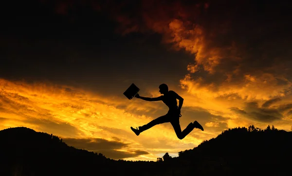 Silhouette of a man with a briefcase - jump at sunset — Stock Photo, Image