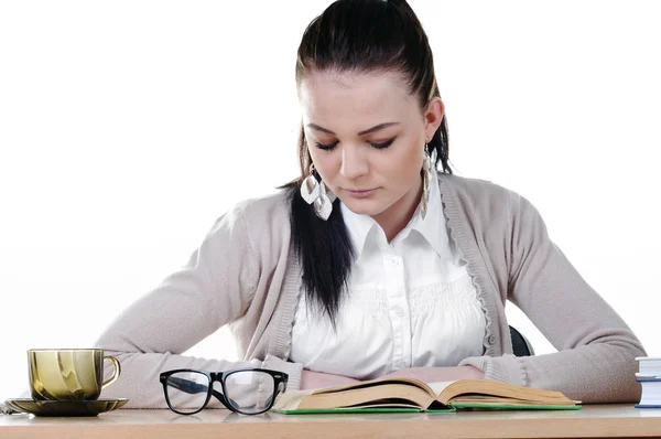 Studentin liest ein Buch am Tisch, isoliert auf weiß — Stockfoto