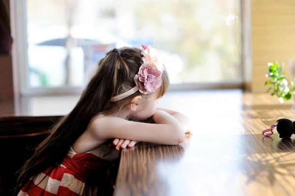 Litlle meisje zitten aan een tafel in een restaurant — Stockfoto