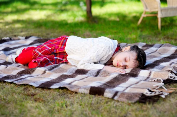 Mädchen schläft auf Plaid im Garten — Stockfoto