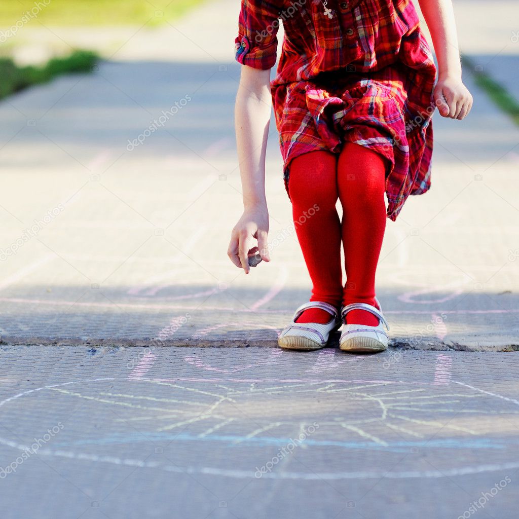 Child girl playing hopscotch on asphalt