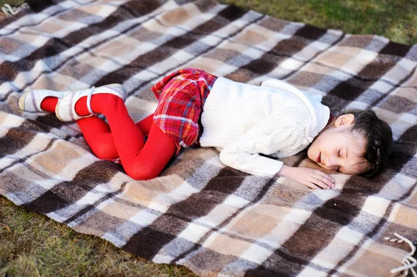 Muchacha del niño durmiendo en cuadros en un jardín — Stockfoto